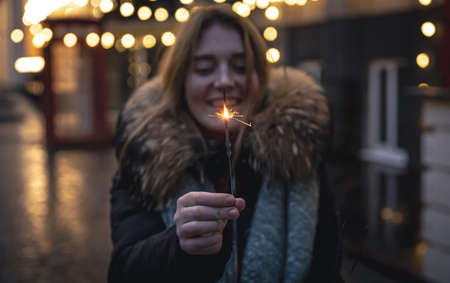 Burning sparklers in the hands of a young woman in the dark.の写真素材