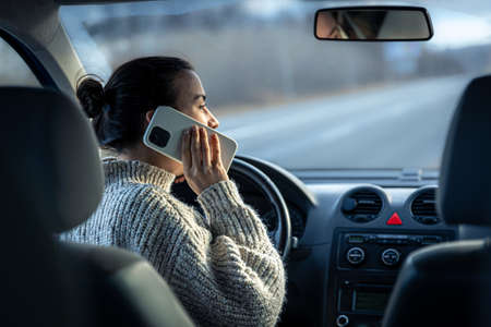 Young woman talking on the phone while driving a car.の写真素材