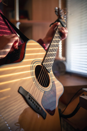 Girl with a guitar in the sunlight through the blinds.