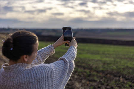 Young woman makes a photo of the field by smartphone.の写真素材