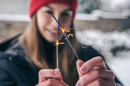 Close-up young woman holding sparklers in her hands.の写真素材
