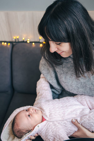 A young mother with a newborn baby girl in her arms.