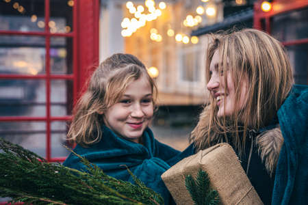 A little girl and young woman with thuja branches and a gift under a plaid.の写真素材