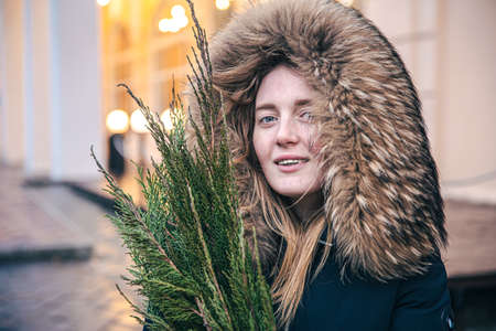 A young woman holding thuja branches, blurred background with bokeh lights.の写真素材
