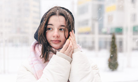 Portrait of a teenage girl outdoors with a smartphone in snowy winter weather.