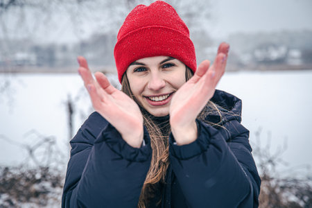 Cheerful young woman froze in her hands in the cold.の写真素材