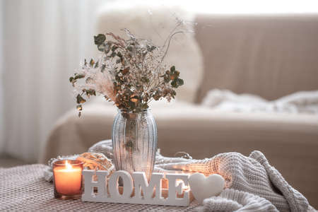 Cozy composition with decorative word home, candles and vase with dried flowers.の写真素材