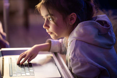 A little girl uses a laptop late at night.の写真素材
