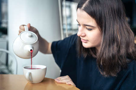 Close-up of a young woman pours tea from a teapot.の写真素材