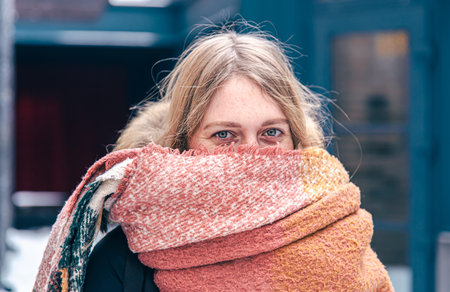 Portrait of a cute young woman wrapped in a scarf in winter.
