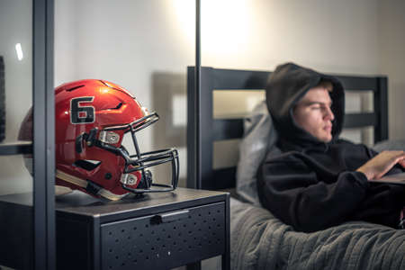 A teenager guy sits in a room on a bed and uses a laptop.の写真素材