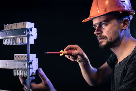 A male electrician works in a switchboard with an electrical connecting cable.の写真素材