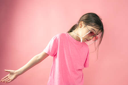 Stylish little girl girl in sunglasses on a pink background.の写真素材