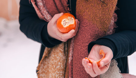 Close-up, a woman peels a tangerine, blurred background.