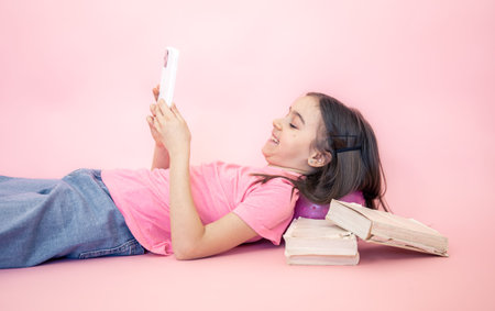 Little girl with a smartphone in her hands on a pink background, copy space.
