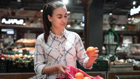 A young woman chooses fruits in a supermarket.の写真素材