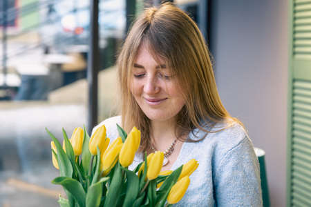 Beautiful young woman with a bouquet of yellow tulips.の写真素材