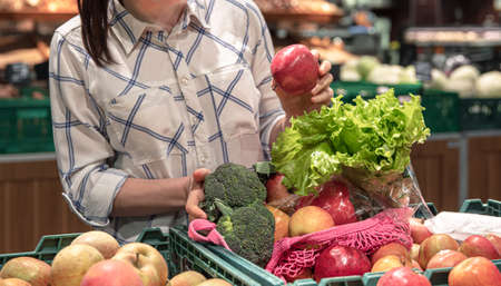 A young woman chooses fruits and vegetables in a supermarket.の写真素材