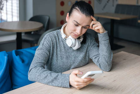 A young woman in white headphones and with a smartphone.の写真素材