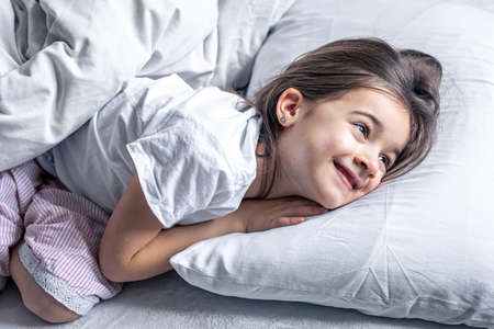 A cute little girl lies in bed and doesnt want to get up.の写真素材