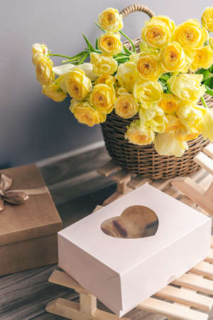 Basket with yellow flowers and gift box, copy space.の写真素材