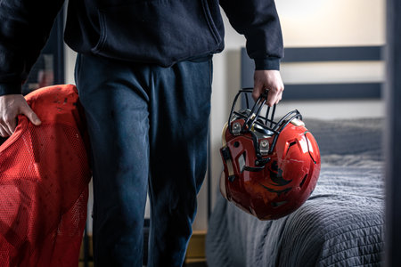A young man with a football helmet in his room.の写真素材