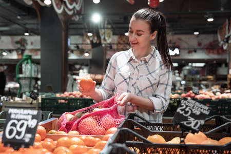 A young woman chooses fruits in a supermarket.の写真素材