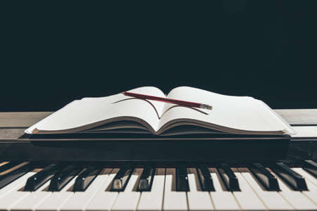 Open notepad on piano keys in the dark, copy space.の写真素材