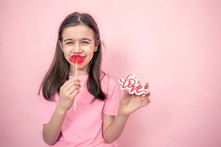 Funny little girl with a lip-shaped lollipop in her hands, copy space.の写真素材