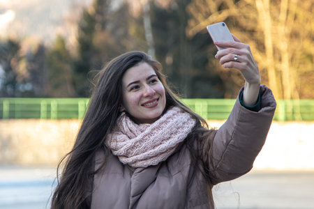 A young woman takes a selfie on a walk in the mountains.