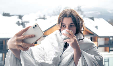 A young woman takes a selfie in the mountains on a hotel balcony.の写真素材
