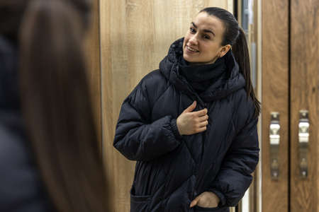 A young woman looks at herself in a closet mirror.の写真素材