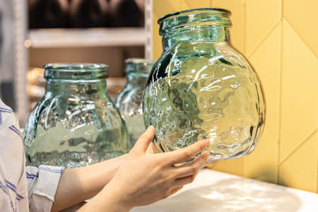 Close-up, a glass jar in female hands on a shop window.の写真素材