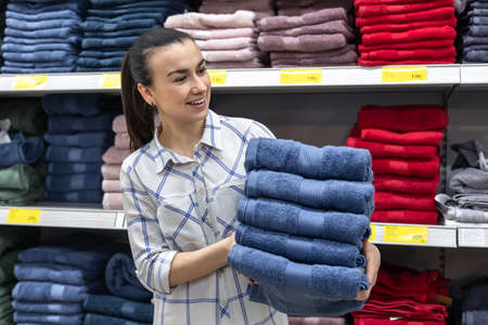A young woman with a stack of towels in a home improvement store.の写真素材