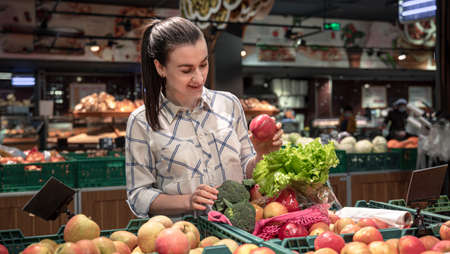 A young woman chooses fruits and vegetables in a supermarket.の写真素材