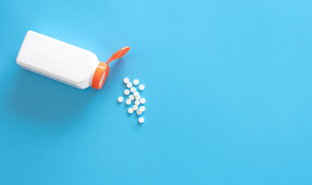 Pills are poured out of a jar on a blue background., flat lay.