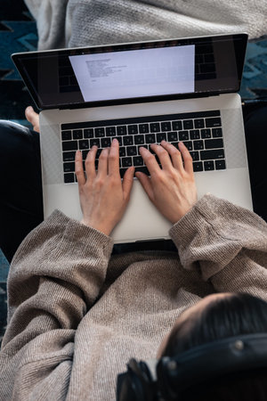 A woman working sitting at a laptop, top view.