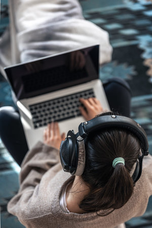 A woman working sitting at a laptop, top view.