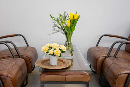 A bouquet of flowers on a table in an interior with leather armchairs.の写真素材
