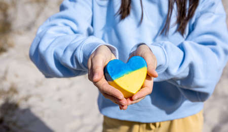 Close-up, heart in the color of the flag of Ukraine in female hands.の写真素材