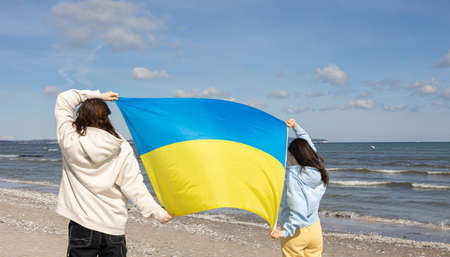 Two young women with the flag of Ukraine on the background of the sea.の写真素材