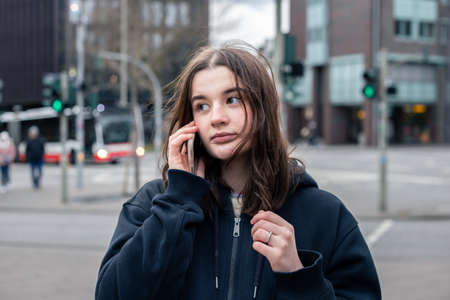 A young woman talking on the phone in the city on the street.の写真素材