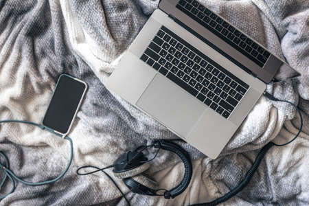Laptop, smartphone and headphones in bed, top view.の写真素材