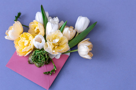 Flower composition in an envelope on a blue background, flat lay.
