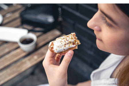 Close-up, a woman eats an appetizing eclair.