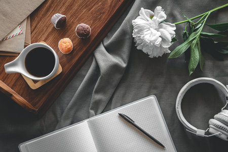 Flat lay composition in bed, with coffee and notepad.
