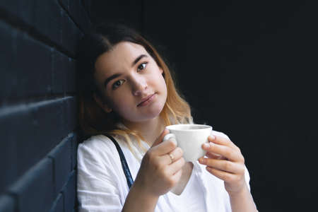 A young woman with coffee cup in black cafe interior.の写真素材