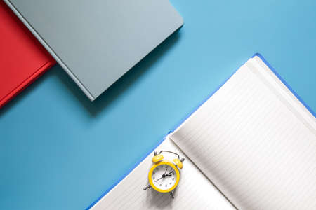 Flat lay, notepads and alarm clock on blue background.の写真素材