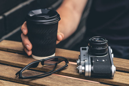 Vintage film camera and a glass of coffee on a wooden table.の写真素材