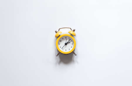 Yellow alarm clock on a white background isolated, flat lay.の写真素材